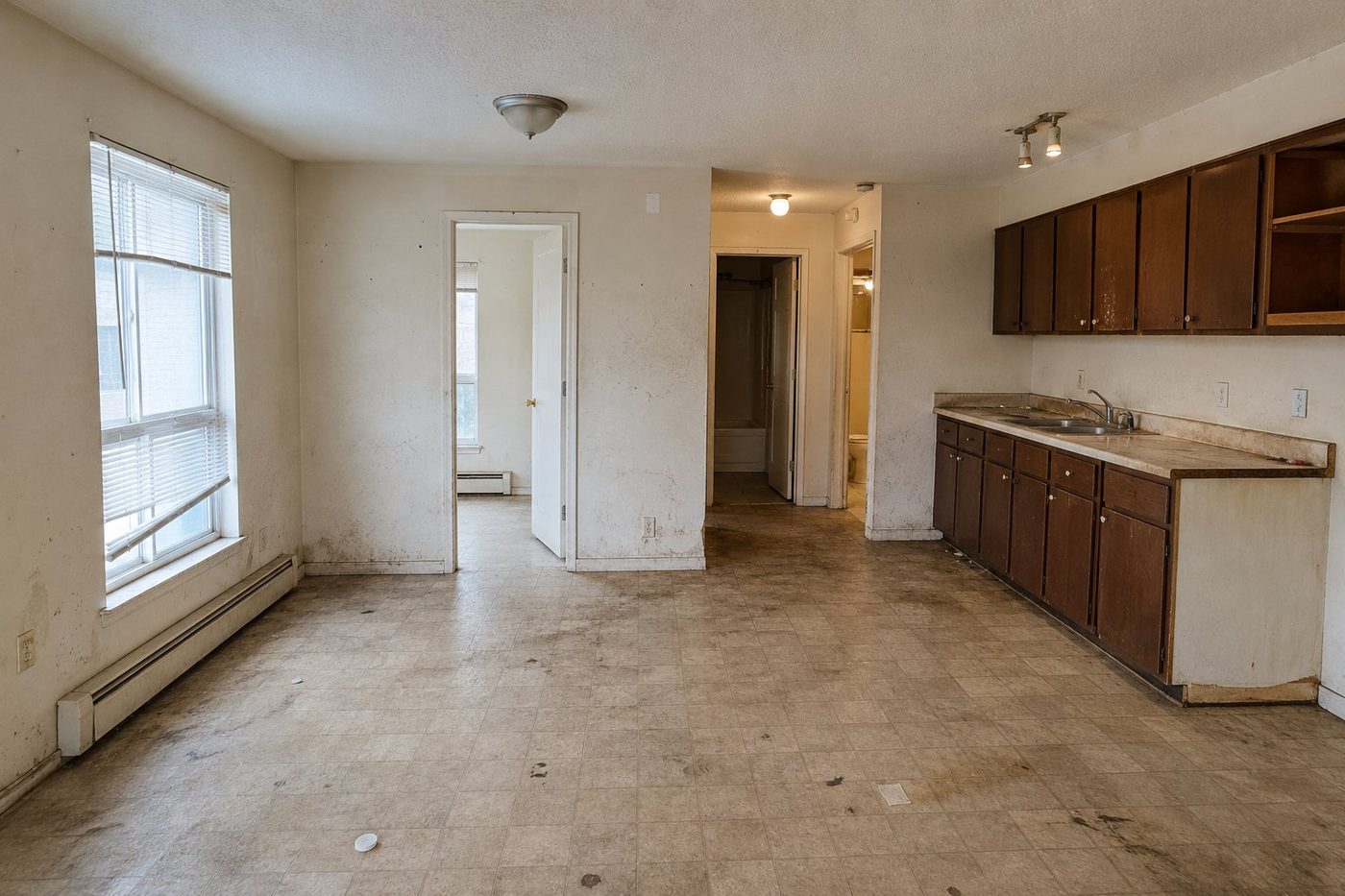 Unit as-is before reset, worn floors and marked walls